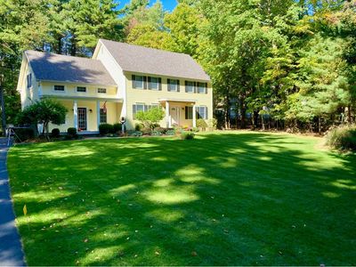 Cute yellow colonial home in West Sand Lake, NY with vibrant green lawn in front of deciduous tree l