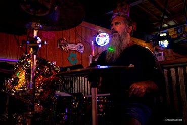 Long bearded man playing drums on stage