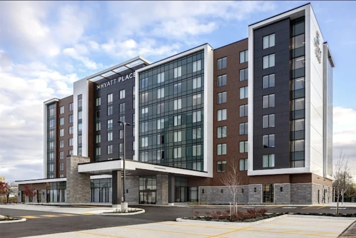 Modern Hyatt Place hotel building with a glass facade and ample parking.