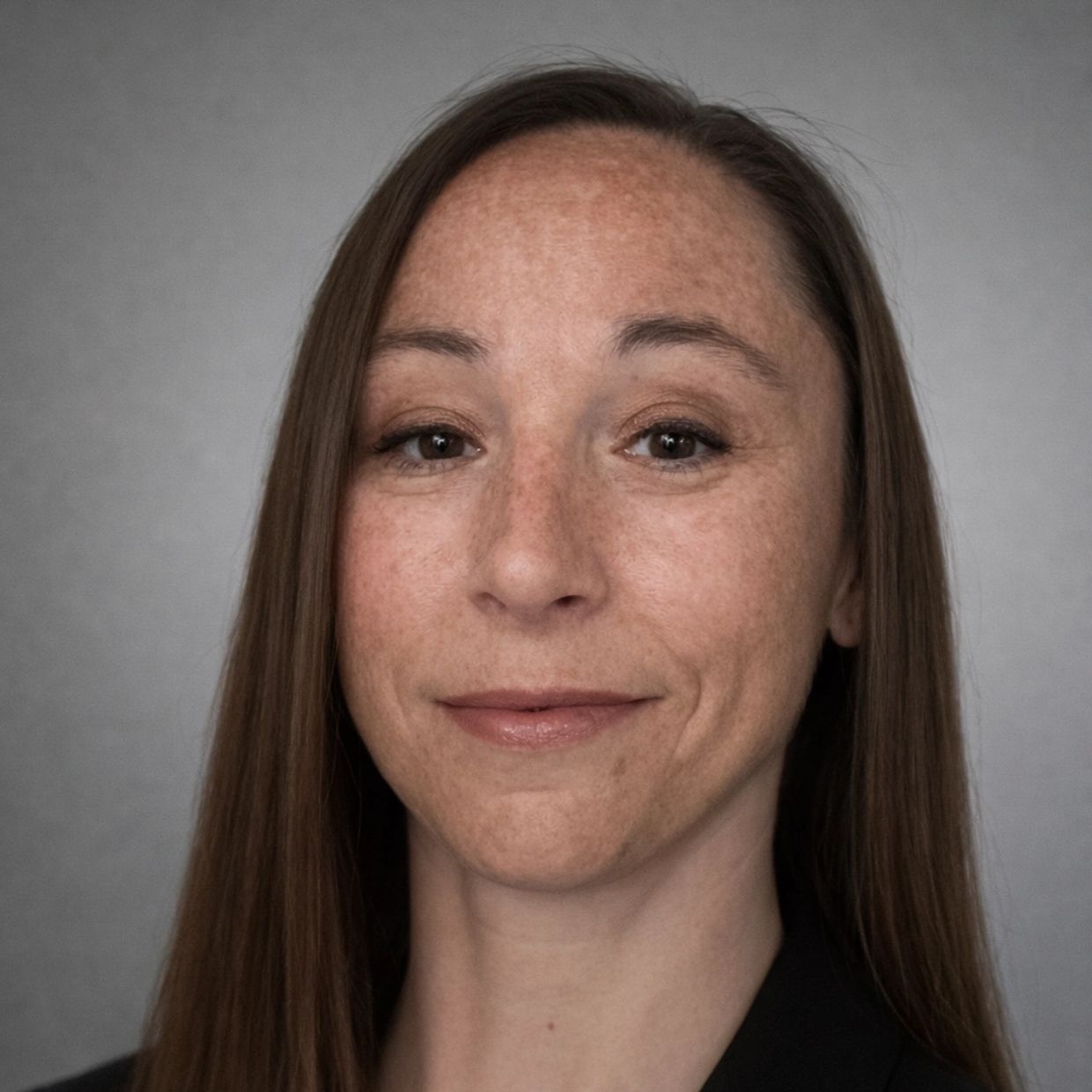 Close-up portrait of a smiling woman with straight brown hair.