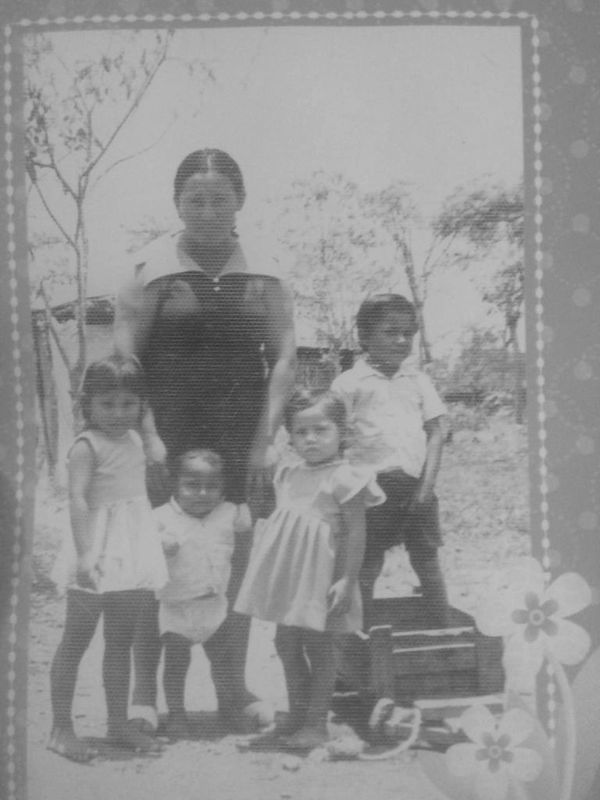 A vintage photo of a woman with four children outdoors.