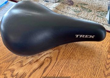 Black TREK bicycle seat on a wooden surface.