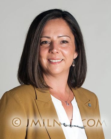 Professional woman smiling, wearing a brown blazer and white blouse.