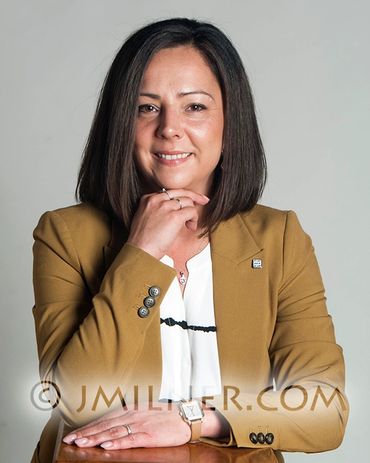 Professional woman in a mustard blazer smiling confidently.