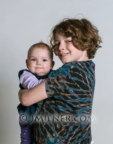 Older child holding a baby, both smiling gently.