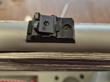 Black metal mounting bracket attached to a cylindrical surface with screws.