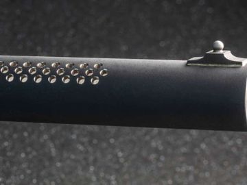 Close-up of a black rifle barrel with ventilation holes and a front sight.