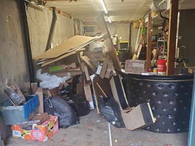 Cluttered basement with piles of boxes and furniture.