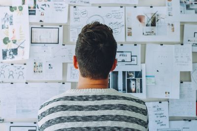 person reviewing wall with posted papers showing creative process