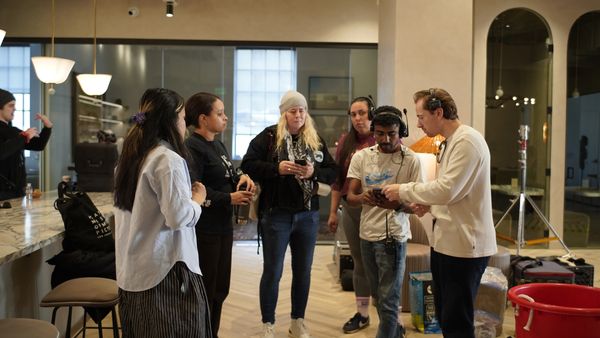 A group of people in a modern office setting discussing something on a phone.