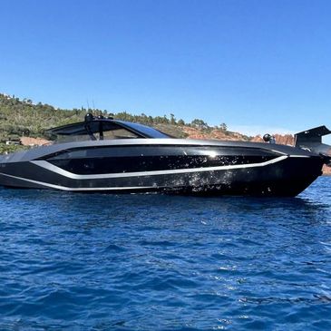 A sleek black luxury yacht cruising on clear blue waters.