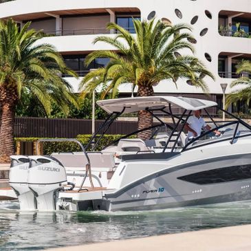 Modern motorboat docked near palm trees and white building.