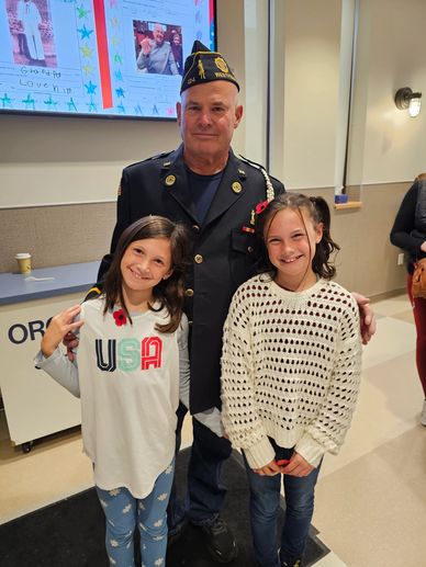 Veteran with two smiling girls indoors.