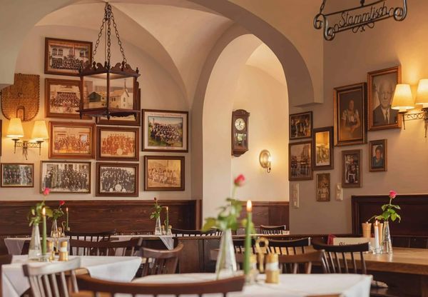 Cozy vintage restaurant interior with wooden tables and framed photographs.