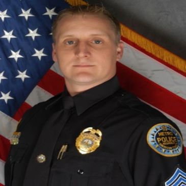 Headshot of Gerry Hyder standing in uniform in front of the American flag