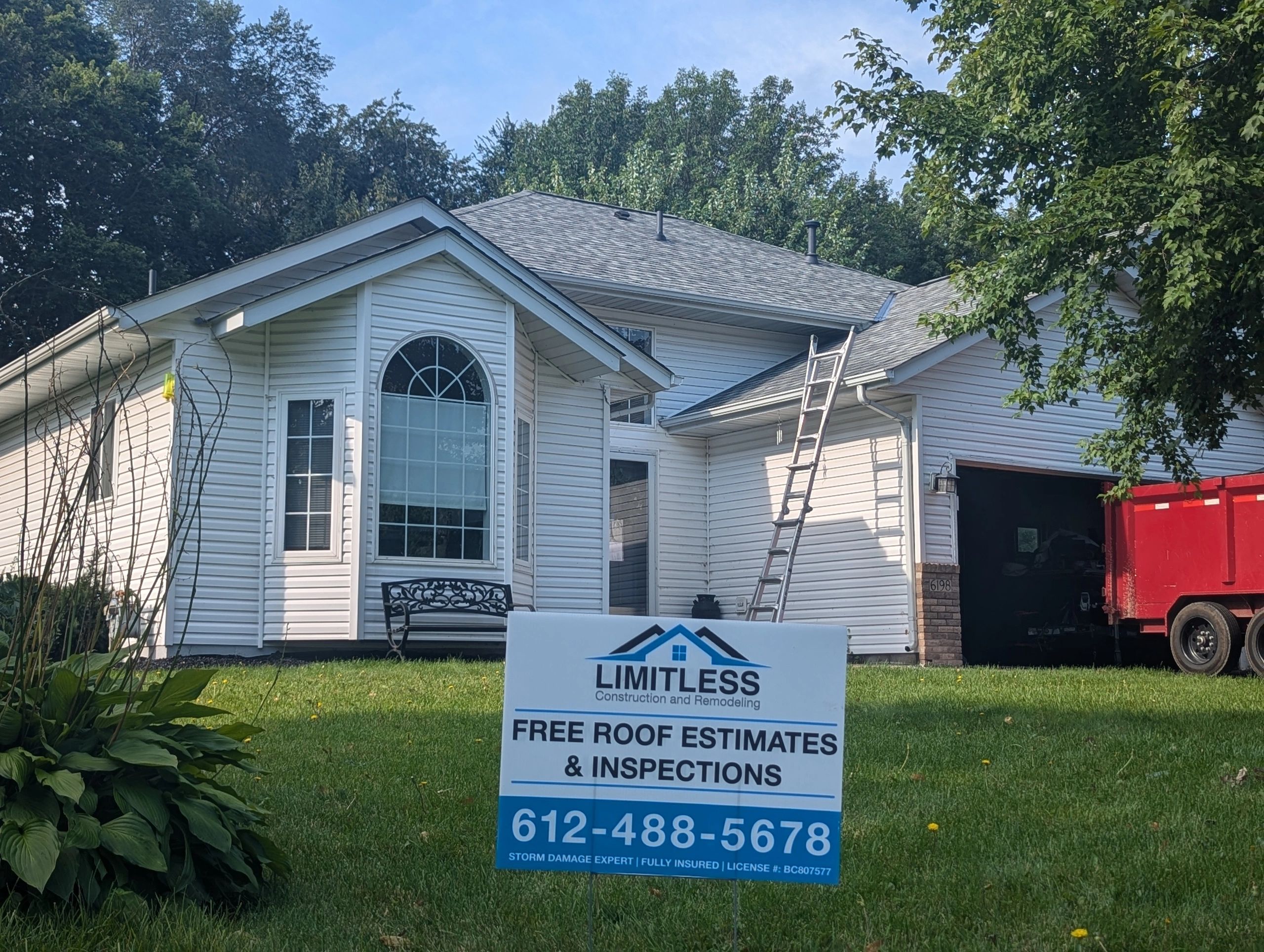 House with a roofing company sign and ladder for repairs.