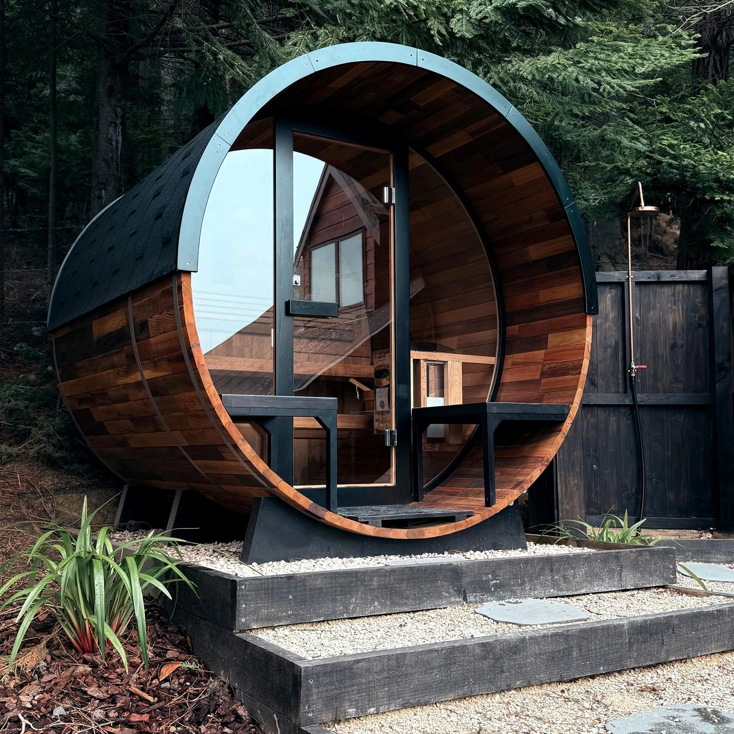 A cylindrical wooden cabin with a glass door in a forest.
