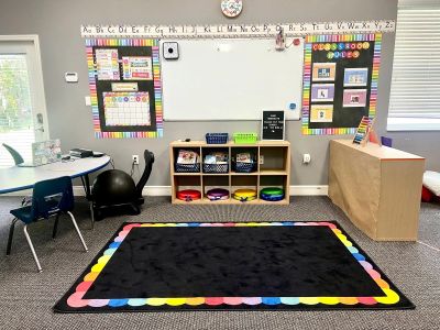 Bright, organized classroom corner with alphabet display and colorful rug.