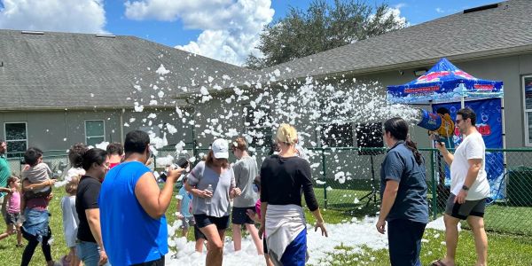 People enjoying a foam party outdoors on a sunny day.