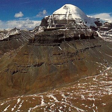 Snow-capped mountain peak under a partly cloudy blue sky.