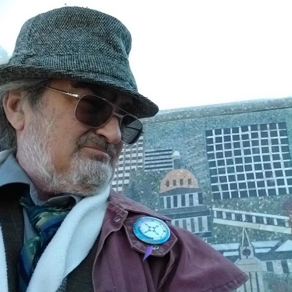 Man in hat and sunglasses with mosaic cityscape background.