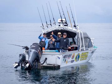 Four men on a fishing boat with fishing rods raised.