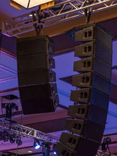 مكبرات صوت كبيرة مكدسة على شكل صفيف خطي، مرتبة لنظام صوتي احترافي للفعاليات، تعرض خدمات تكنولوجيا الصوت وحلول الصوت عالية الجودة من شركة رزق للفعاليات.