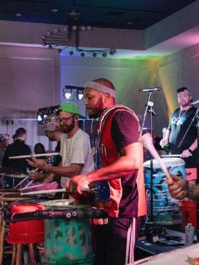 عرض موسيقي حي على المسرح مع إضاءة ملونة وآلات موسيقية، لعرض خدمات الترفيه وأعمال إنتاج الفعاليات التي تقدمها شركة رزق إيفنتس.