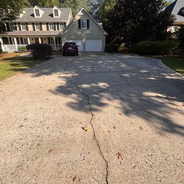 Large house with two-car garage and a wide cracked driveway.