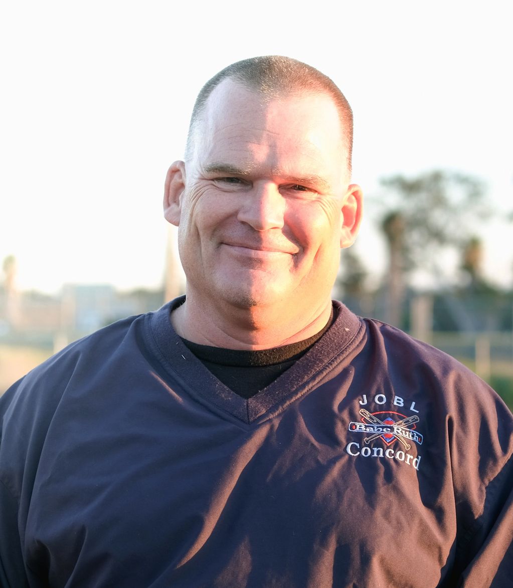 Man smiling outdoors in sports attire.