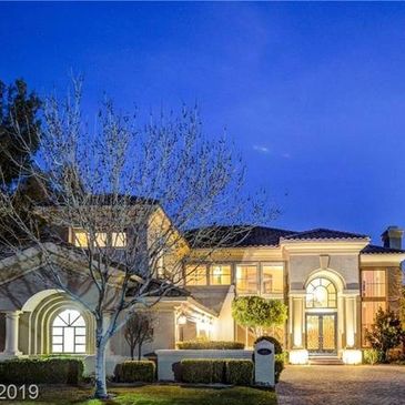 Elegant house illuminated at dusk with a clear blue sky backdrop.