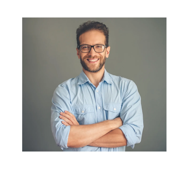 Smiling man with glasses and crossed arms in a light blue shirt.