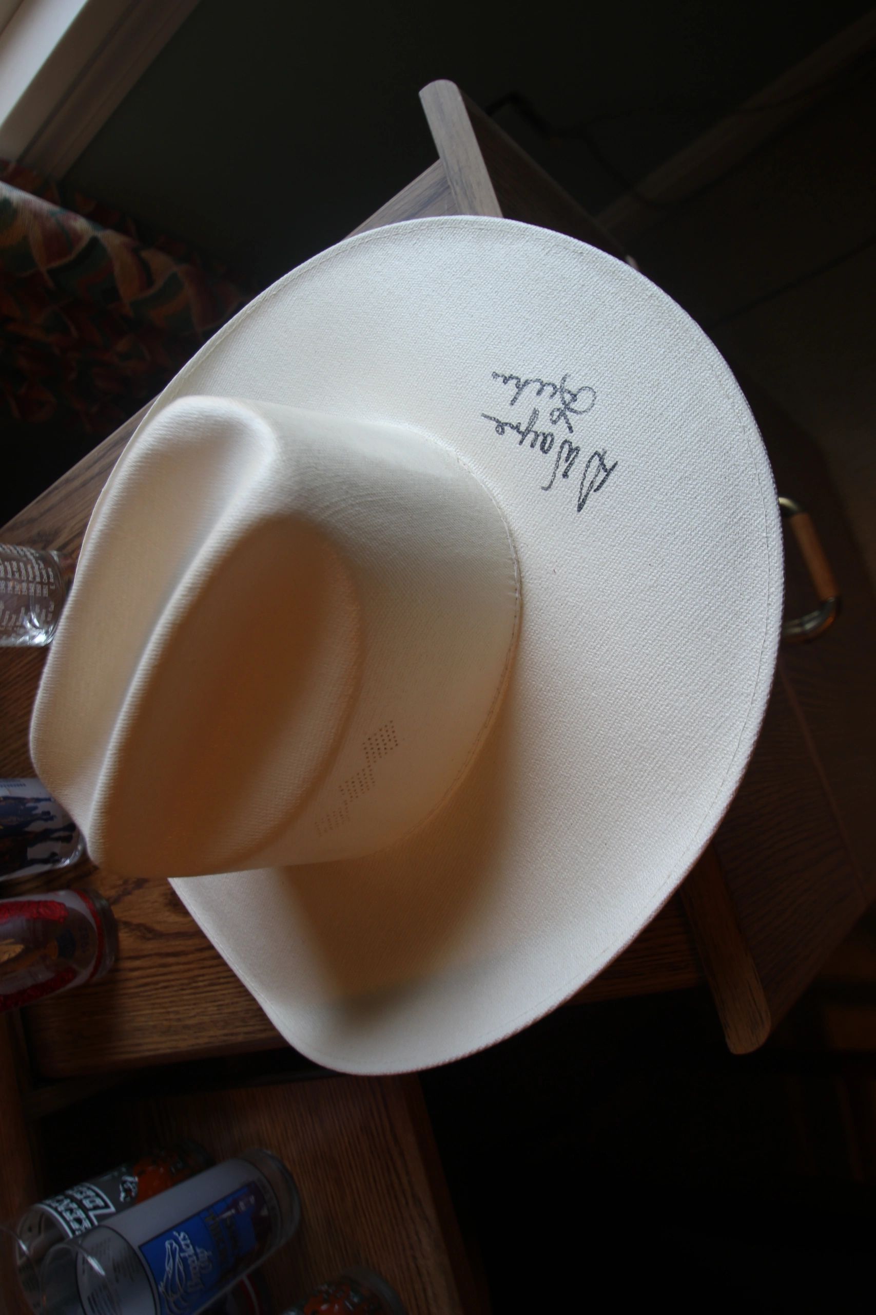 White cowboy hat with a signature on the brim.