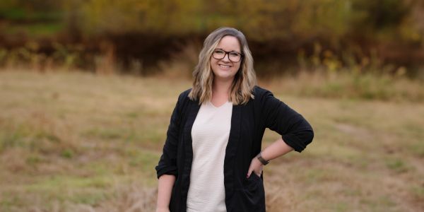 Smiling woman standing outdoors in casual outfit.