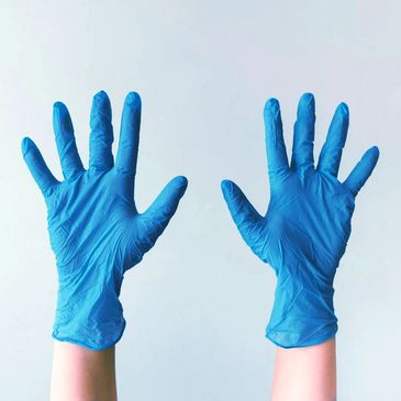 Blue gloves on outstretched hands, plain white background,