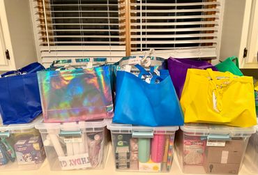 Colorful reusable tote bags arranged on storage bins under a window.