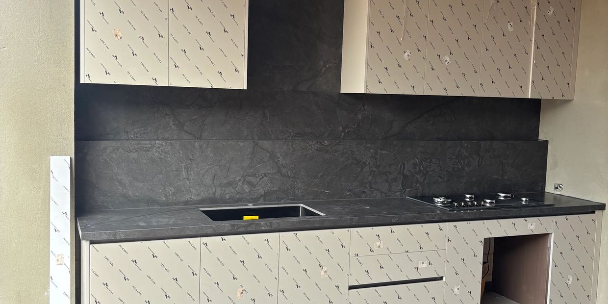 Modern kitchen under construction with protective film on cabinets.