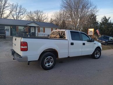 White pickup truck parked outside a house with some rust on the wheel arches.