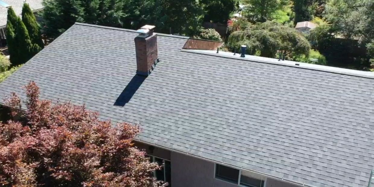 A house roof with a chimney casting a shadow under bright sunlight.