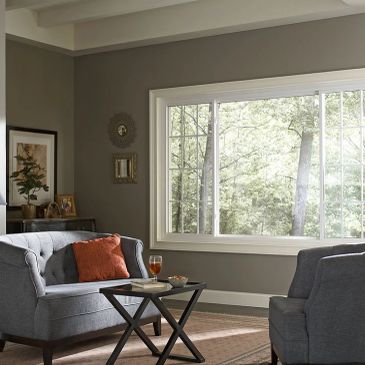 Cozy living room with gray sofas and large window overlooking trees.