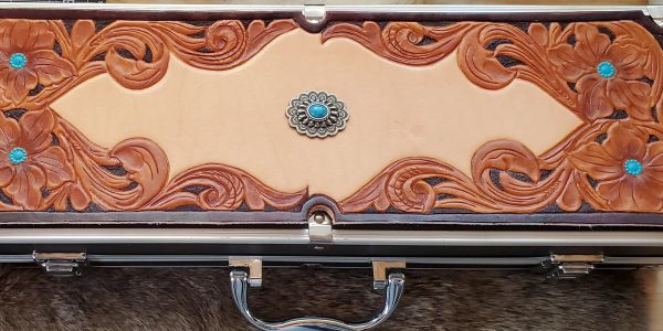 Intricately carved leather BBQ case with floral and swirl designs and turquoise accents.