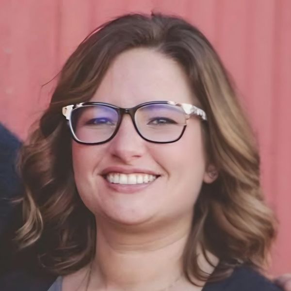 Smiling woman with glasses and wavy hair.