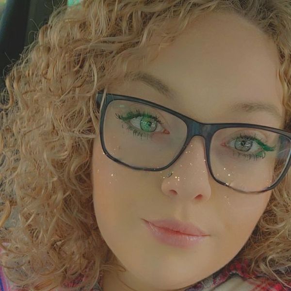 Close-up of a woman with curly hair and glasses.