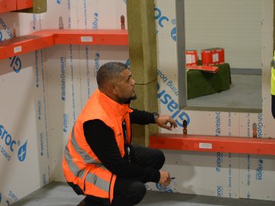Worker points at shelving while kneeling.