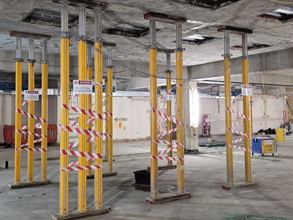 Yellow support props in a construction site with warning tapes.