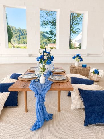 Cozy low wooden table setup with blue and white cushions and floral centerpiece.
