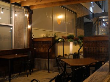 Cozy outdoor seating area with wooden tables and string lights at night.