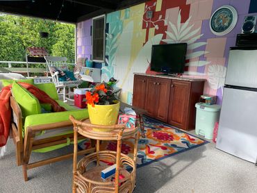 Boring back deck converted to tropical oasis with a custom mural and bright outdoor furniture.