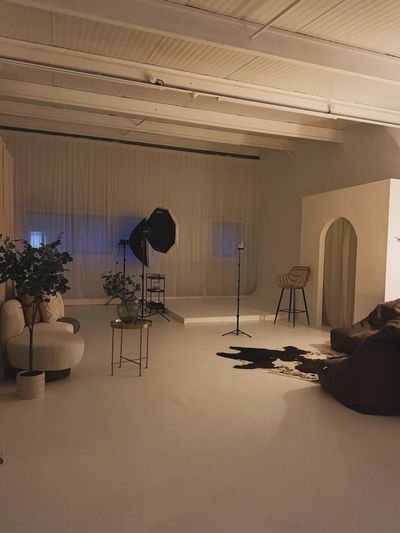 Cozy, dimly lit studio with plants, seating, and photography equipment.
