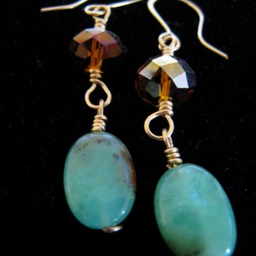 Elegant earrings with green oval stones and faceted brown beads on gold hooks.